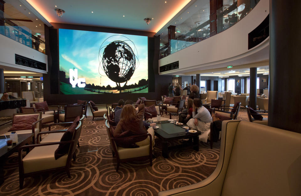 Passengers watch a New York-themed video in the Atrium of the Norwegian Cruise Line's new ship, Norwegian Breakaway, which was christened in New York, Wednesday, May 8, 2013. Features include a water park with five water slides including free fall slides, plus a three-story sports complex with nine-hole mini-golf, a basketball court and rock-climbing wall.(AP Photo/Richard Drew)