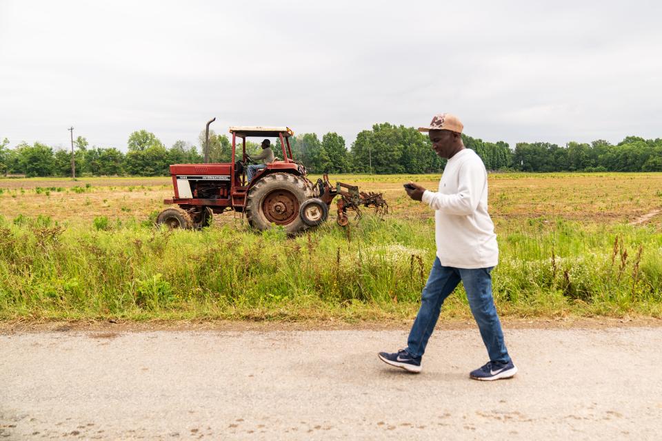 Calvin Head of the Mileston Farming Cooperative walks down a dirt road near one of the co-op’s fields in May, as LC Mitchel drives his tractor.