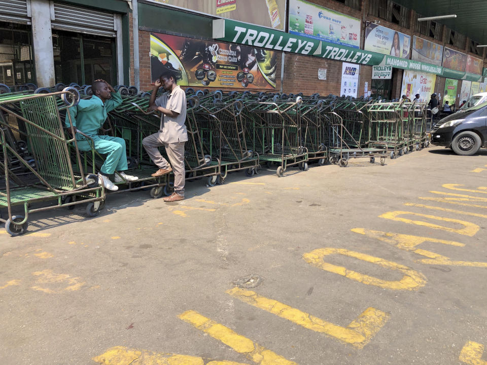 Vendors who make a living from pushing customer trollies, wait for customers outside a supermarket in Harare, in this Wednesday, Oct, 9, 2019 photo. Hyperinflation is changing prices so quickly in the southern African nation that what you would see displayed on a supermarket shelf might change by the time you reach the checkout. (AP Photo/Tsvangirayi Mukwazhi)