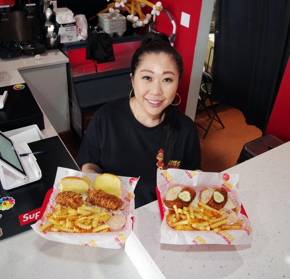 Vivian Chow, founder and owner of Birdies Hot Chicken in Brockton, stands with two of her most popular chicken dishes on Wednesday, March 30, 2022. Chow says that her meals can be prepared at several levels of spiciness, which the customer can choose. Birdies has been open for only about a month, but has already become a hot spot for Brockton-area residents. Chow says she got the idea for this style of meal when she visited Nashville, Tennessee, and thought the approach might catch on up north.