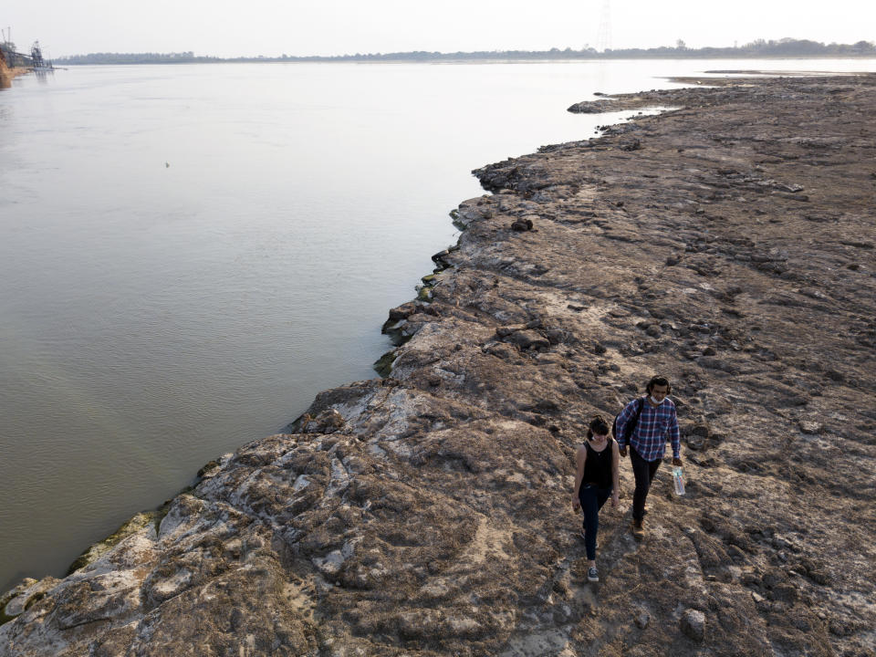 Gente camina sobre los restos de un antiguo volcán expuesto en medio del río Paraguay, en Paraguay, el martes 6 de octubre de 2020. (AP Foto/Jorge Saenz)