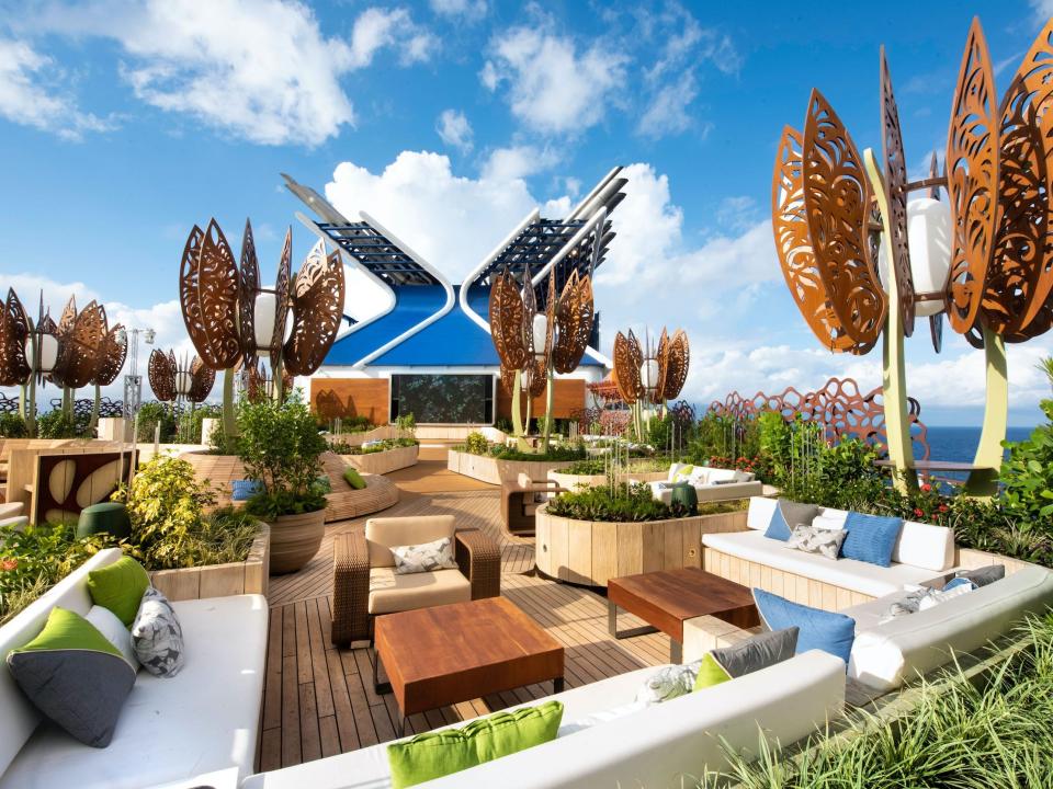 outdoor seating and tables among plants and public art on the rooftop garden of the Celebrity Edge