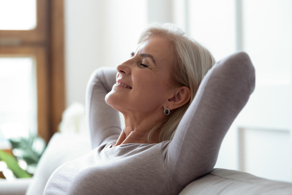 Close up side view of calm happy mature woman lying on sofa at home relax with eyes closed, relaxed senior female take nap or sleep on comfortable couch relieve negative emotion, stress free concept