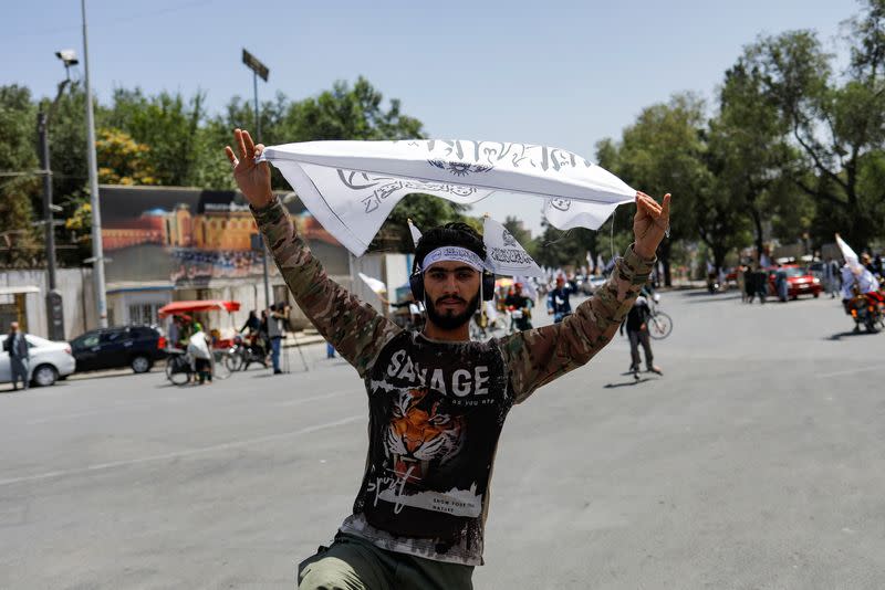 A Taliban supporter holds an Islamic Emirate of Afghanistan flag on the second anniversary of the fall of Kabul on a street near the US embassy in Kabul