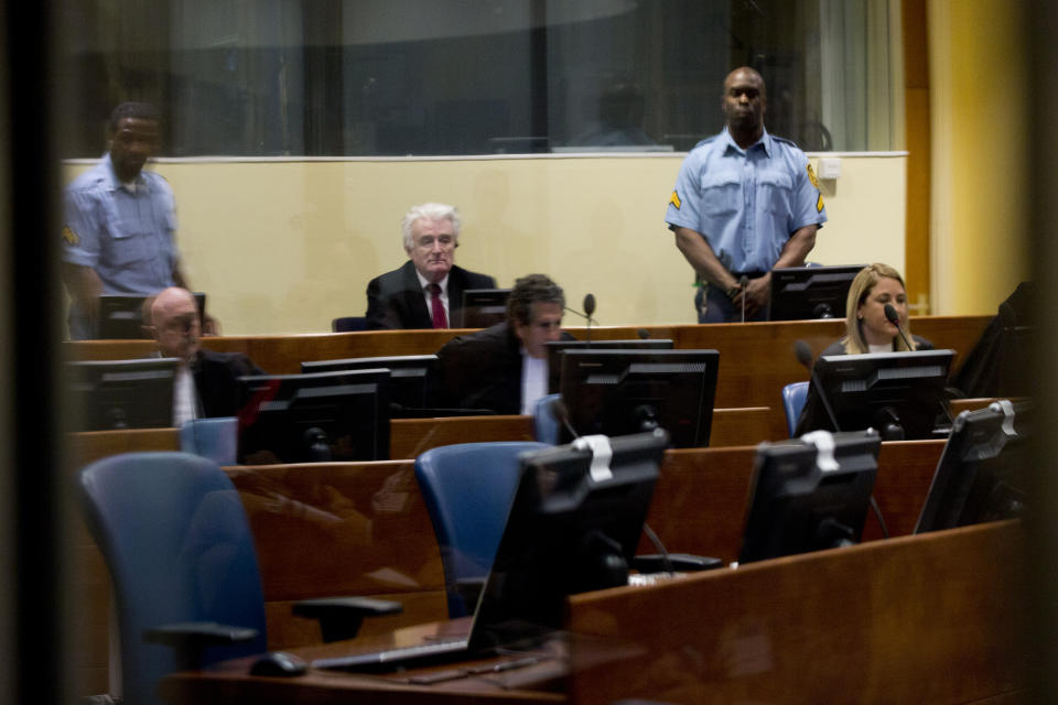 Former Bosnian Serb leader Radovan Karadzic, center, waits for judges to enter the court room of the International Residual Mechanism for Criminal Tribunals in The Hague, Netherlands, Wednesday, March 20, 2019. Nearly a quarter of a century since Bosnia's devastating war ended, Karadzic is set to hear the final judgment on whether he can be held criminally responsible for unleashing a wave of murder and destruction. United Nations appeals judges will on Wednesday rule whether to uphold or overturn Karadzic's 2016 convictions for genocide, crimes against humanity and war crimes, as well as his 40-year sentence. (AP Photo/Peter Dejong, Pool)