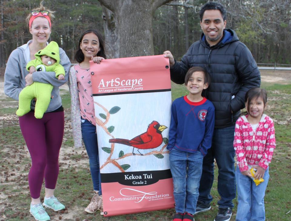 Second grader Kekoa Tui and Tui's family poses with Tui's banner after the ArtScape Youth Banner reveal last week at Jackson Park.