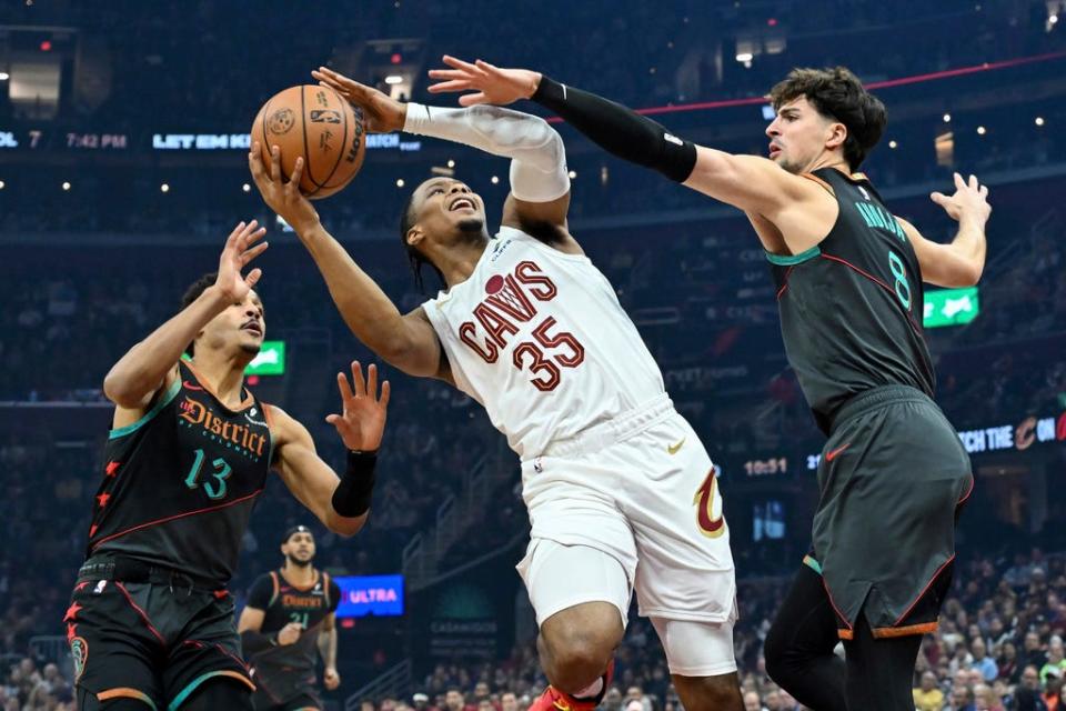 Cleveland Cavaliers' Isaac Okoro (35) drives against Washington Wizards' Deni Avdija (8) and Jordan Poole (13) during the first half of an NBA basketball game Friday, Jan. 5, 2024, in Cleveland. (AP Photo/Nick Cammett)