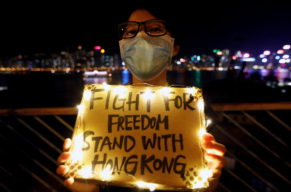 A woman holds a placard as protesters hold hands to form a human chain during a rally to call for political reforms along Tsim Sha Tsui and Hung Hom Promenade in Hong Kong, China, August 23, 2019.&nbsp; (Photo: Willy Kurniawan/Reuters)