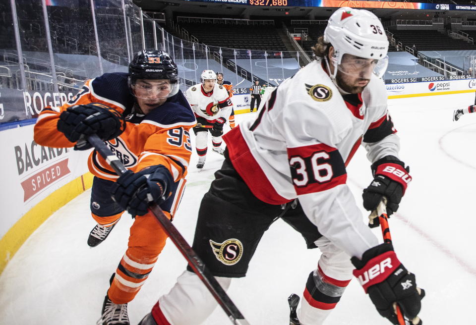 Edmonton Oilers' Ryan Nugent-Hopkins (93) and Ottawa Senators' Colin White (36) battle for the puck during second-period NHL hockey game action in Edmonton, Alberta, Monday, March 8, 2021. (Jason Franson/The Canadian Press via AP)