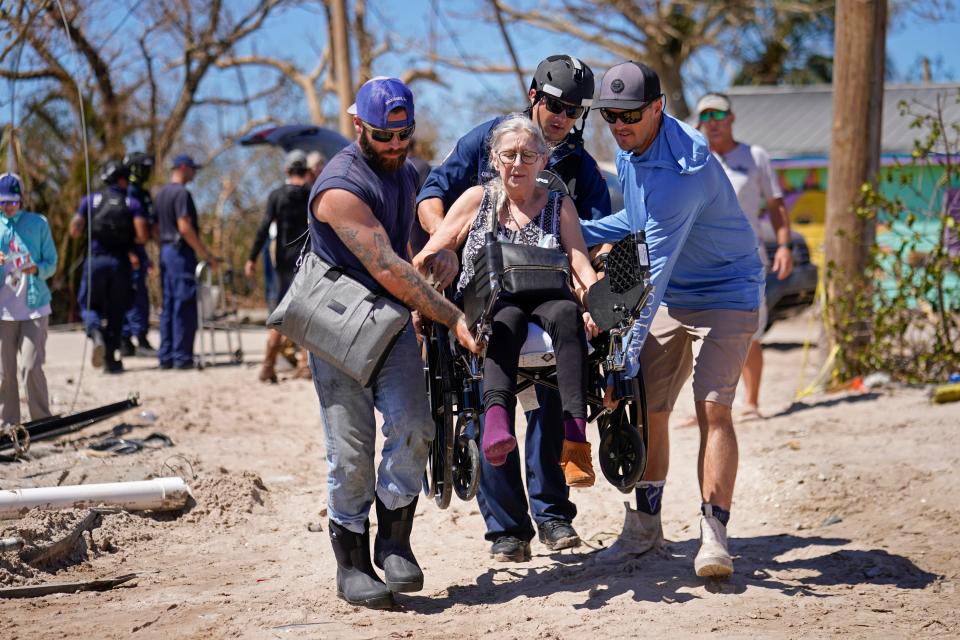 Rescuers help evacuate Suzanne Tomlinson, a Pine Island resident who rode out Hurricane Ian, on Sunday. The only bridge to the island is heavily damaged so it can only be reached by boat or air.