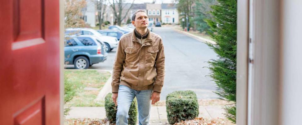 Young man standing on front porch of his new home