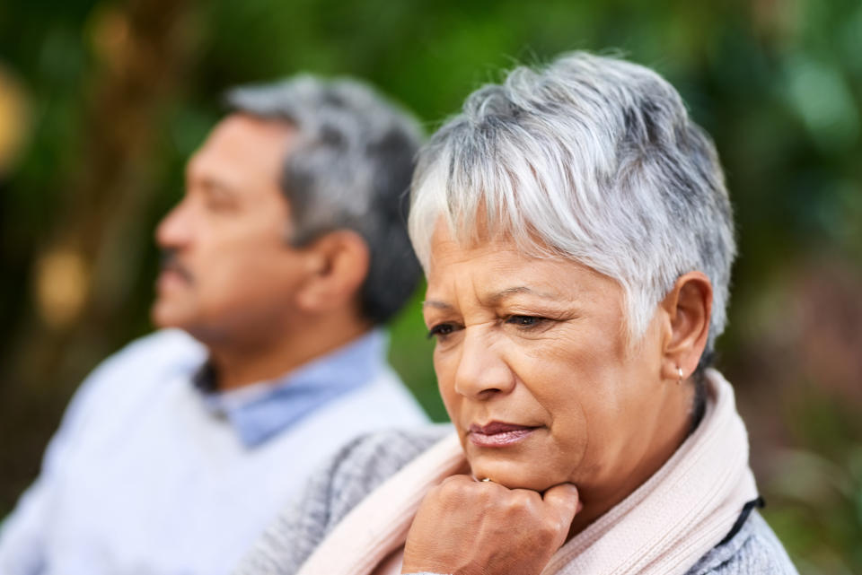 Shot of a mature woman looking upset with her husband in the background