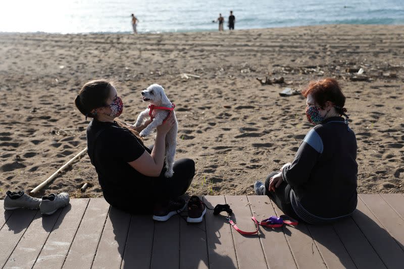 Mujeres disfrutan del clima soleado en la playa de la Barceloneta, en Barcelona