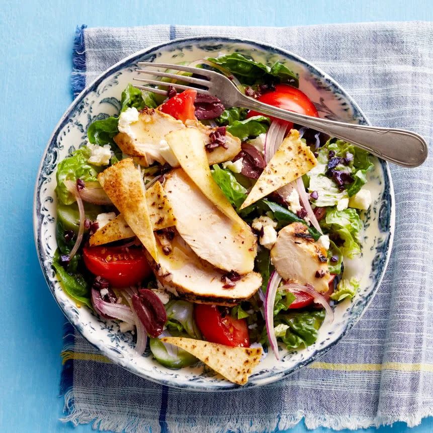 greek salad with chicken overhead in bowl with blue background