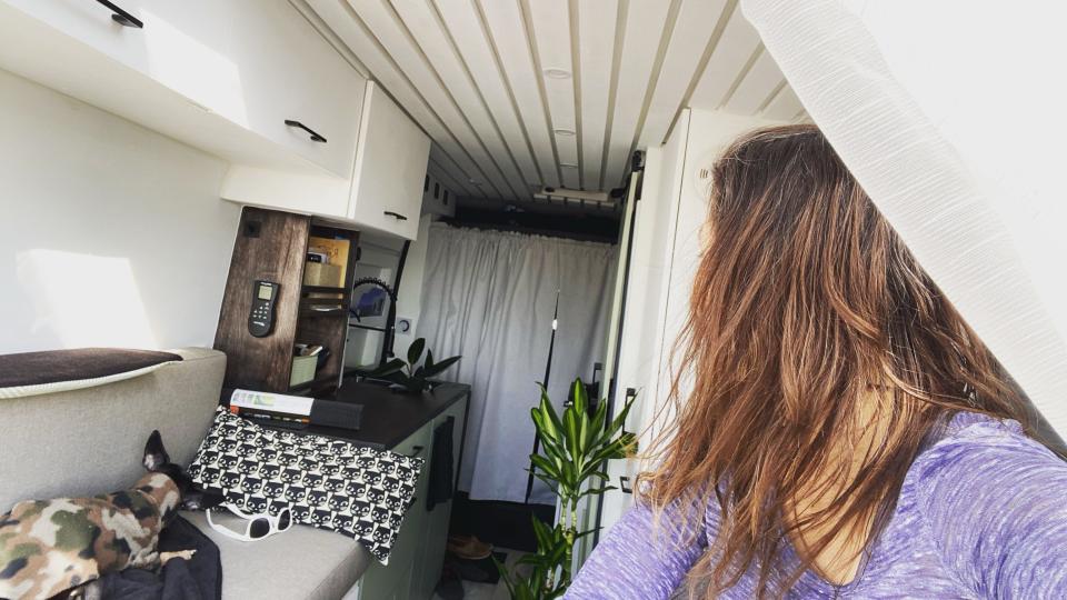 Side of woman's head as she looks back into van with kitchen counter and sofa