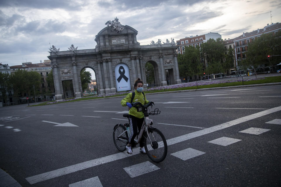 Una mujer espera un cambio de luz frente a la Puerta de Alcalá en Madrid el 25 de abril del 2020. La pandemia de coronavirus está dando nuevo impulso a las bicicletas como alternativa al trasporte público. (AP Photo/Manu Fernández)