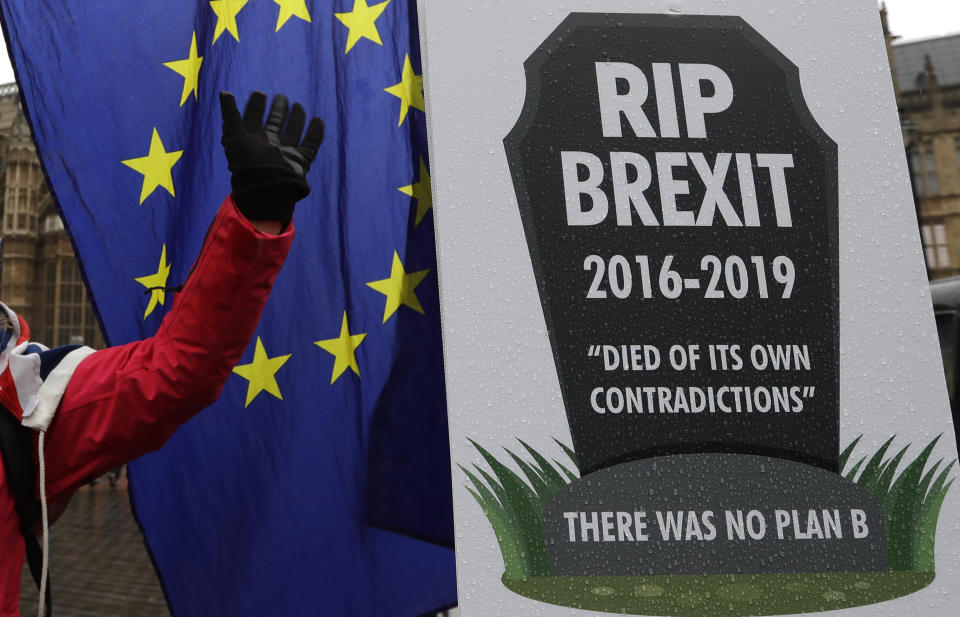 An anti Brexit demonstrator waves to traffic alongside a banner tied to railings outside parliament in London, Thursday, Jan. 24, 2019. The European Union's chief Brexit negotiator, Michel Barnier, is rejecting the possibility of putting a time limit on the "backstop" option for the Irish border, saying it would defeat the purpose. (AP Photo/Kirsty Wigglesworth)