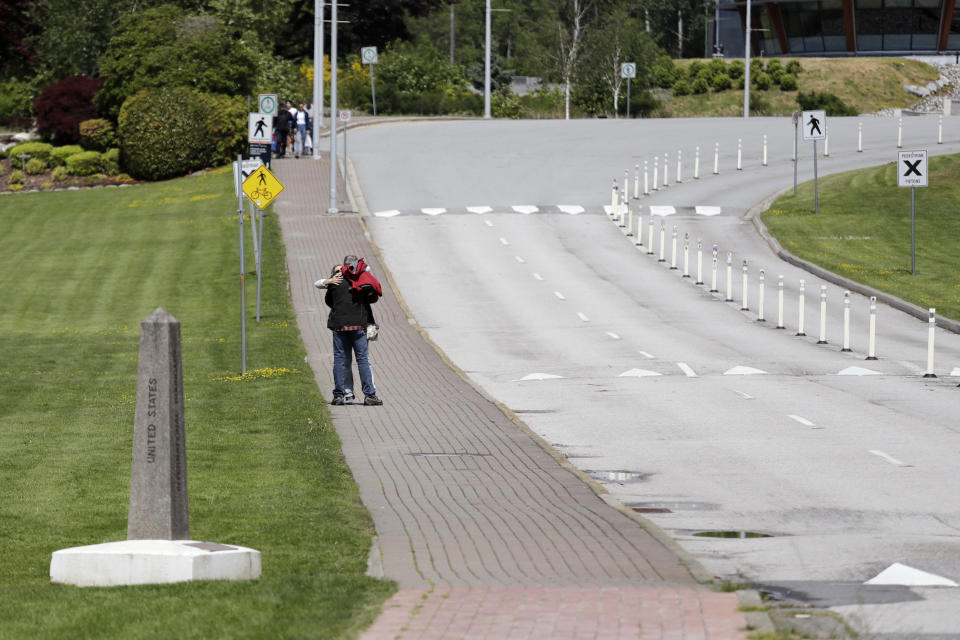 In this photo taken May 17, 2020, two people embrace after meeting at the border between the U.S. and Canada at Peace Arch Park, where traffic is almost nonexistent, in Blaine, Wash. With the border closed to nonessential travel amid the global pandemic, families and couples across the continent have found themselves cut off from loved ones on the other side. But the recent reopening of Peace Arch Park, which spans from Blaine into Surrey, British Columbia, at the far western end of the 3,987-mile contiguous border, has given at least a few separated parents, siblings, lovers and friends a rare chance for some better-than-Skype visits. (AP Photo/Elaine Thompson)