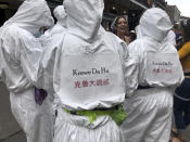 Mardi Gras revelers sport hazmat suits in a spoof of epidemic scares, Tuesday Feb. 25, 2020, on Bourbon Street in New Orleans. (AP Photo/Kevin McGill)