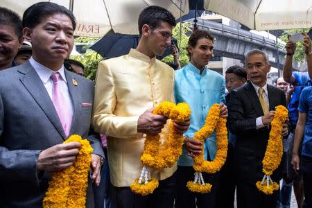 Novak Djokovic of Serbia (2nd L) and Rafael Nadal of Spain (2nd R) hold flower garlands as they pray during their visit to the Erawan shrine, ahead of Friday's tennis friendly match called "Back To Thailand - Nadal vs Djokovic", in Bangkok, Thailand, October 2, 2015 . REUTERS/Athit Perawongmetha