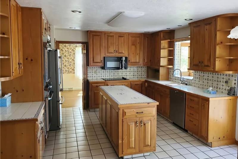 Wooden cabinets and white tiles in the kitchen before renovation.