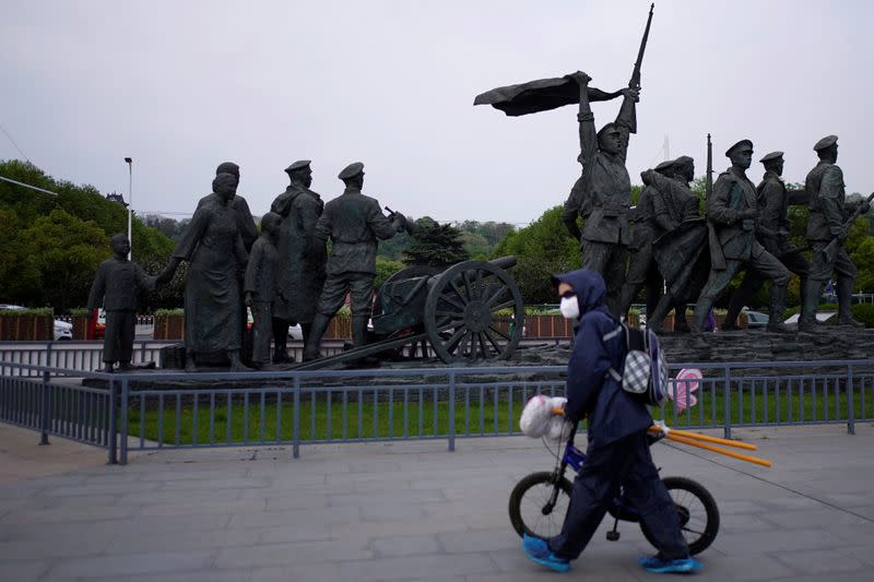 A resident wearing a face mask walks past statue symbolising Xinhai Revolution, a revolution that toppled China's last emperor in 1911, in Wuhan