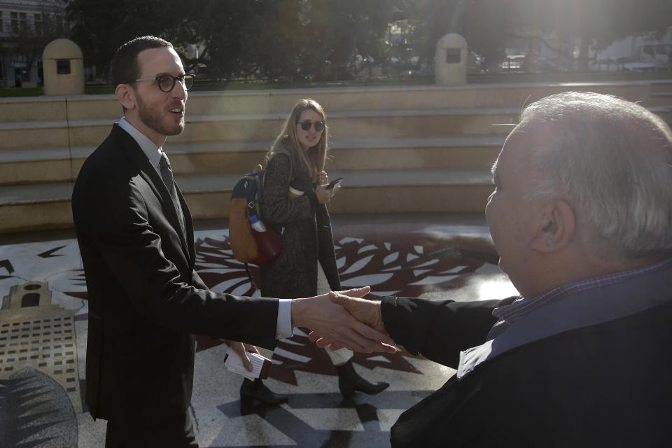 FILE - In this Jan. 7, 2020, file photo, California Sen. Scott Wiener, left, shakes hands with a man after a rally for more housing outside of City Hall in Oakland, Calif. California lawmakers have failed to pass the most ambitious proposal yet to combat a growing housing crisis in the nation's most populous state, voting down legislation Wednesday, Jan. 29, that would have overridden local zoning laws to let developers to build small apartment buildings in neighborhoods reserved for single-family homes. (AP Photo/Jeff Chiu, File)