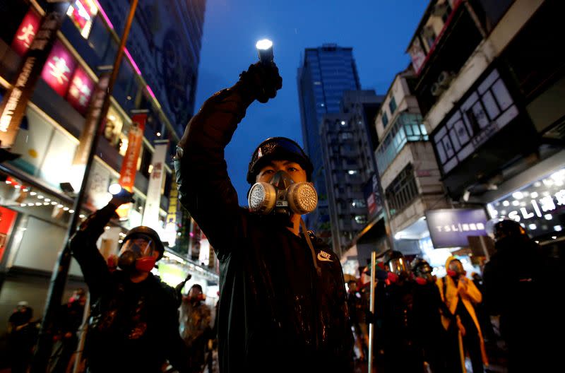 FILE PHOTO: Demonstrators protesting the proposed extradition bill aim their flashlights towards riot police as they are chased through the streets of Hong Kong