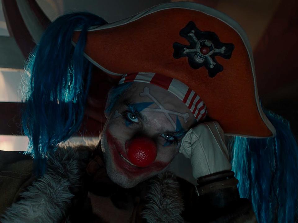 buggy the clown in one piece live action. he has freaky face makeup and a large red nose, with a tricorn hat and long blue hair