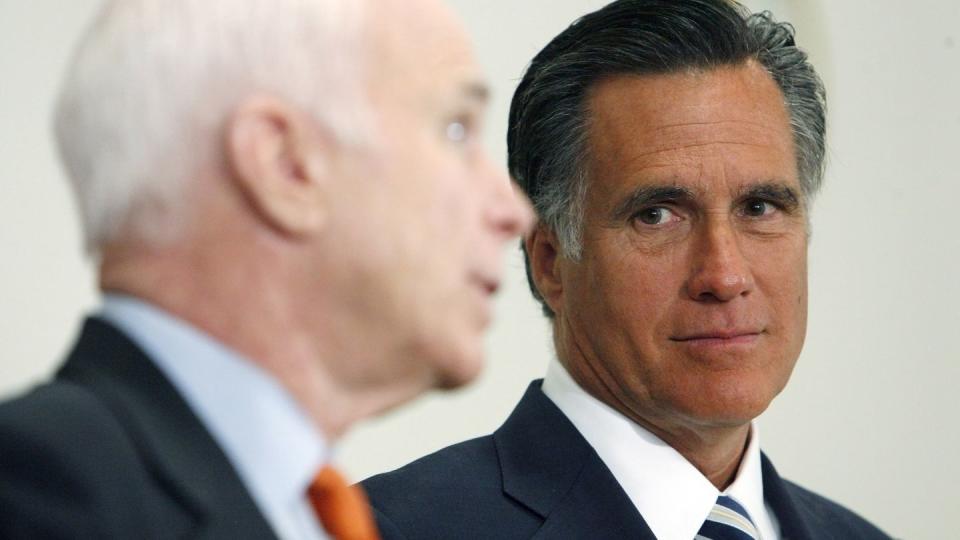 mitt romney, wearing a suit and tie, listens to senator john mccain, who stands in the foreground and talks to someone off camera