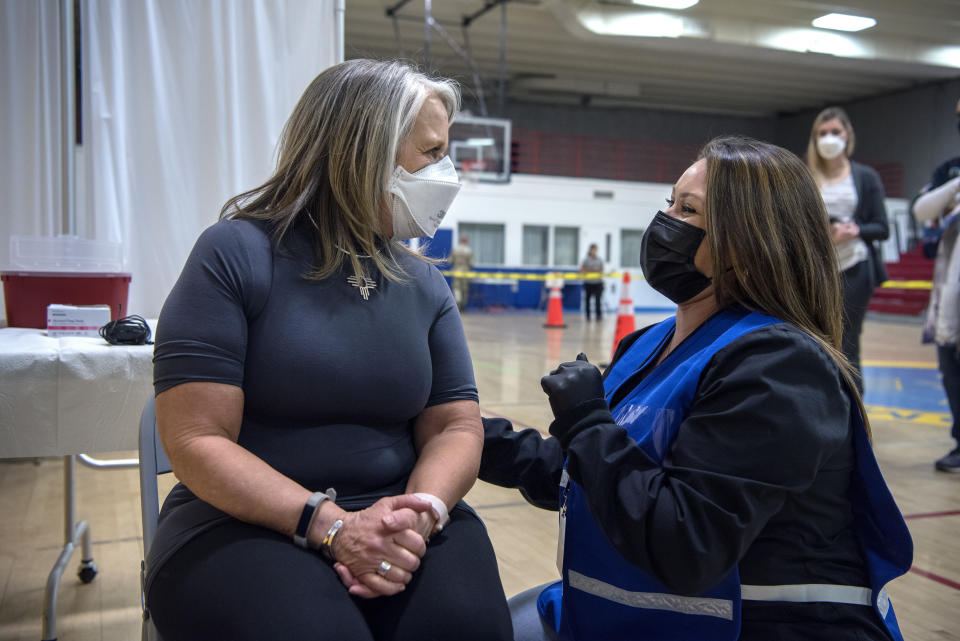 New Mexico Governor Michelle Lujan Grisham talks with Deanne Tapia, a RN with the New Mexico Public Health Office in Santa Fe, before receiving her Pfizer COVID-19 vaccine during a vaccination event held in the gym at Desert Sage Academy in Santa Fe, N.M., Friday March 26, 2021. (Eddie Moore/The Albuquerque Journal via AP, Pool)