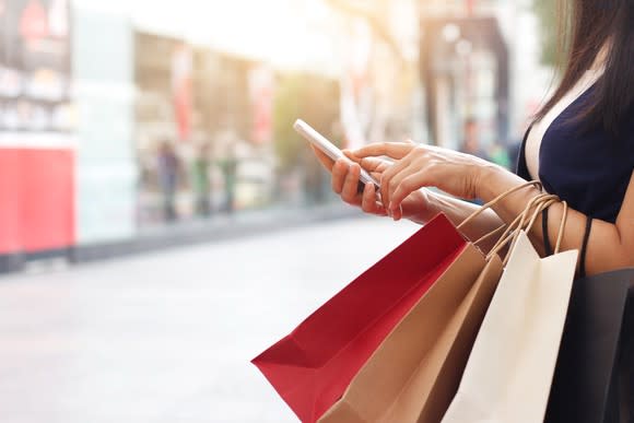 A woman checks her smartphone while shopping.