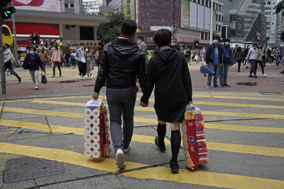 A couple carry a supply of toilet paper at a street on Valentine's Day in Hong Kong, Friday, Feb. 14, 2020. China on Friday reported another sharp rise in the number of people infected with a new virus, as the death toll neared 1,400. (AP Photo/Kin Cheung)