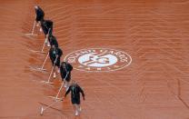 Workers sweep water off a tarp as rain interrupts a men's singles match between Novak Djokovic of Serbia and Joao Sousa of Portugal at the French Open tennis tournament at the Roland Garros stadium in Paris May 26, 2014. REUTERS/Gonzalo Fuentes (FRANCE - Tags: SPORT TENNIS)