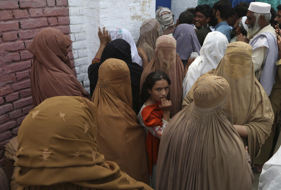 Victims of unprecedented flooding from monsoon rains line up to receive relief aid organized by The International Federation of Red Cross and Red Crescent Societies (IFRC), in Charsadda, Pakistan, Monday, Sept. 5, 2022. The U.N. refugee agency rushed in more desperately needed aid Monday to flood-stricken Pakistan as the nation's prime minister traveled to the south where rising waters of Lake Manchar pose a new threat. (AP Photo/Mohammad Sajjad)