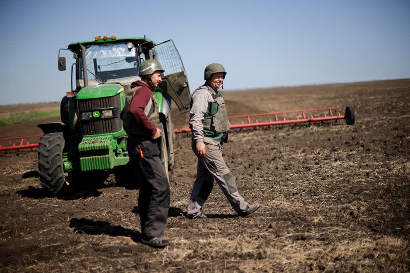 Ukrainian farmers wear body armours to plough frontline fields