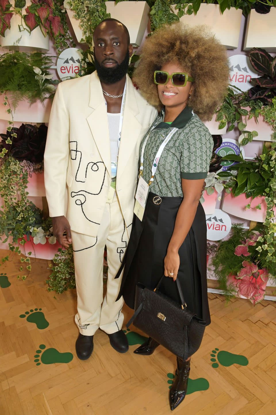 marcel badiane robin and fleur east in fashionable outfits in front of a grassy wall