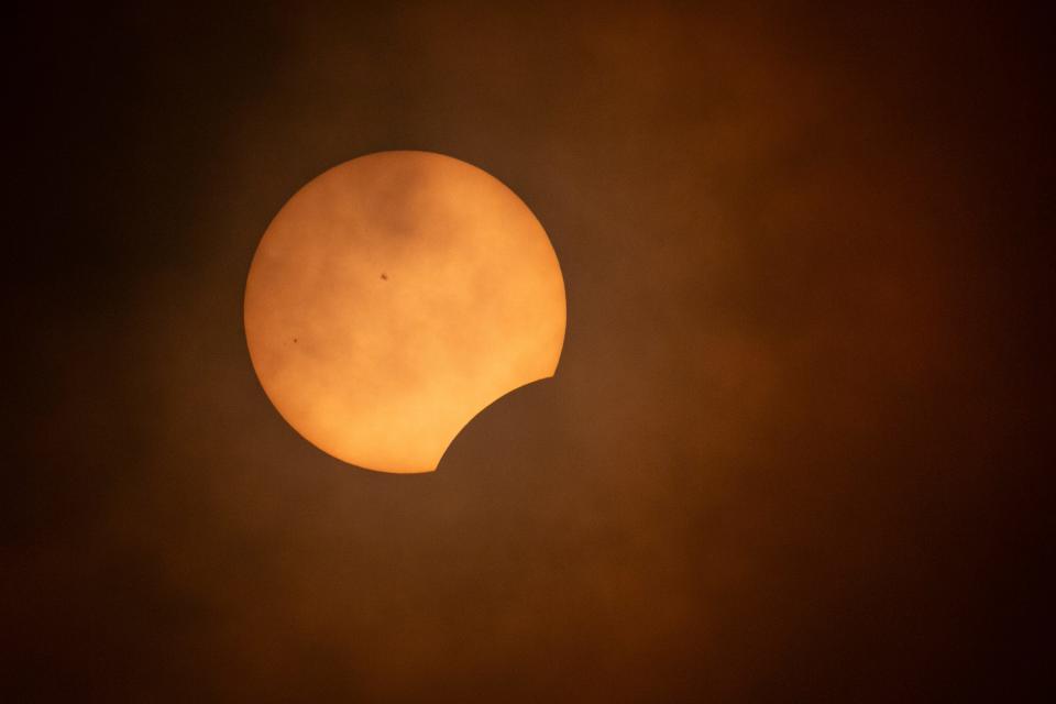 The moon begins to cover the moon during a partial solar eclipse Monday, April 8, 2024, at the College Hill Reservoir in Eugene, Ore.