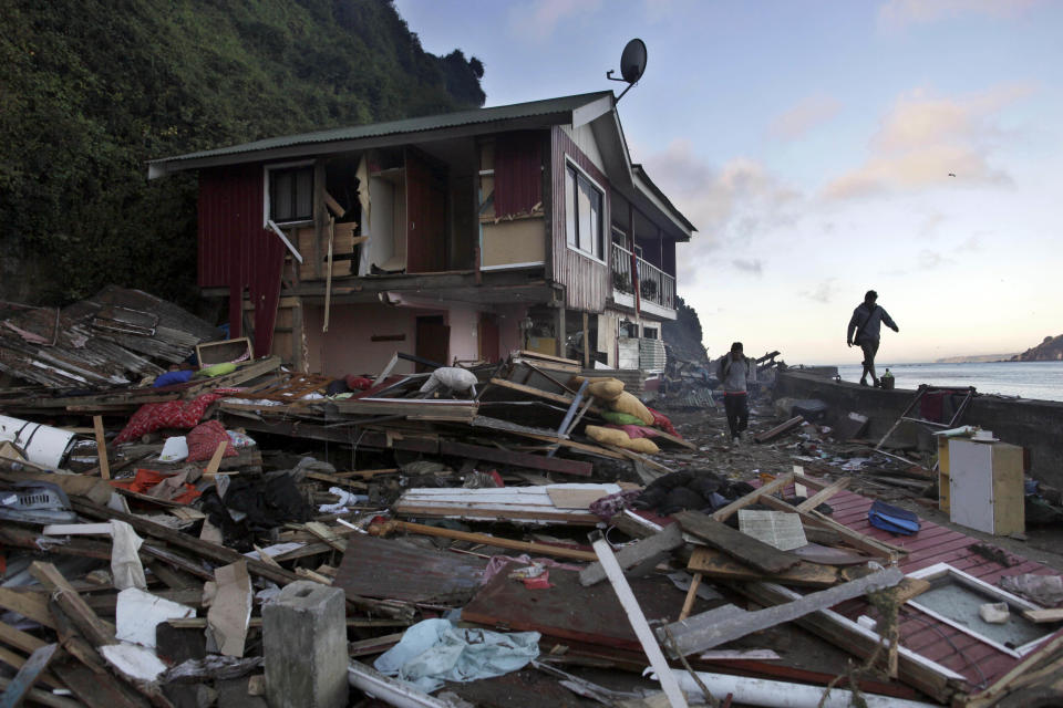 FILE - In this Saturday March 6, 2010 file photo, men walk past an earthquake damaged house in Caleta Tumbes, Chile. Chile marks the two-year anniversary on Monday Feb. 27, 2012 of the tsunami triggered by a magnitude-8.8 earthquake. (AP Photo/Natacha Pisarenko, File)