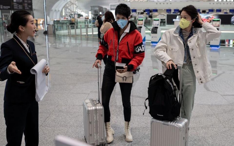 Travelers wearing protective masks at the Daxing international airport in Beijing. | Getty Images