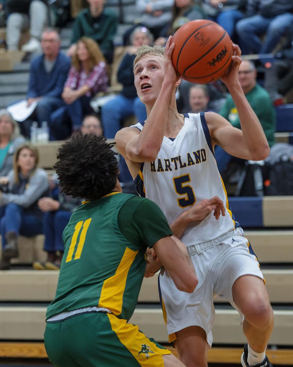 Howell's Jaylen Hicks (11) draws a charge from Hartland's Michael Pennala (5) during the Highlanders' 55-27 victory Friday, Jan. 27, 2023.