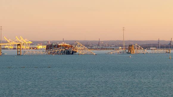 The steel frame of the Francis Scott Key Bridge sits on top of a container ship after it struck the bridge in Baltimore, Maryland, on March 26, 2024. The collapsed sent multiple vehicles and up to 20 people plunging into the harbor below. 