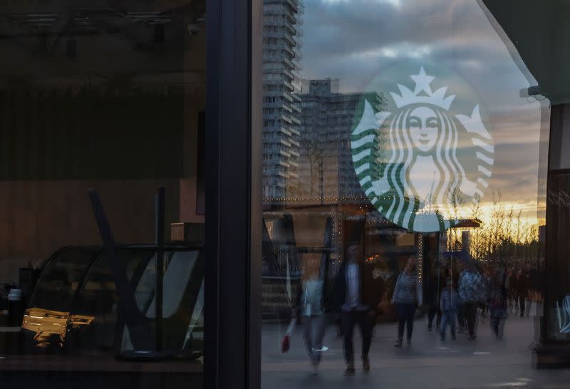 Logo at a closed Starbucks cafe is seen with reflection of people in Moscow