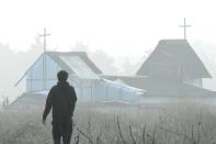 A migrant walks past a makeshift church in the "Jungle" migrant camp in Calais, northern France, on October 23, 2016