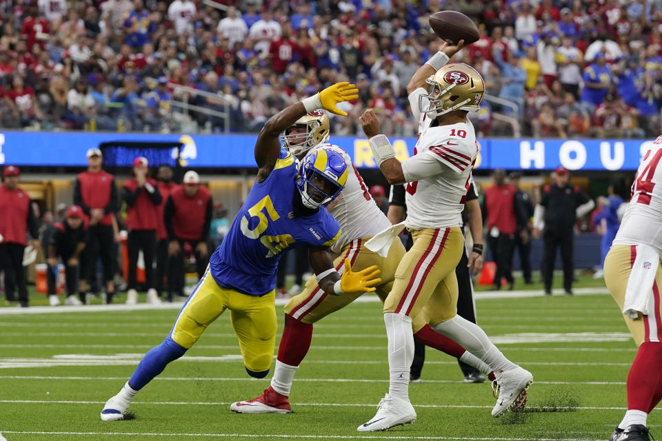San Francisco 49ers quarterback Jimmy Garoppolo, right, throws a touchdown pass to running back Christian McCaffrey as Los Angeles Rams linebacker Leonard Floyd tries to get to him during the second half of an NFL football game Sunday, Oct. 30, 2022, in Inglewood, Calif. (AP Photo/Gregory Bull)