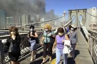 <p>Women wearing dust masks flee across the Brooklyn Bridge from Manhattan to Brooklyn following the collapse of both World Trade Center towers, Sept. 11, 2001, in New York. The towers previously loomed tall in the skyline behind. (Photo:Mark Lennihan/AP) </p>