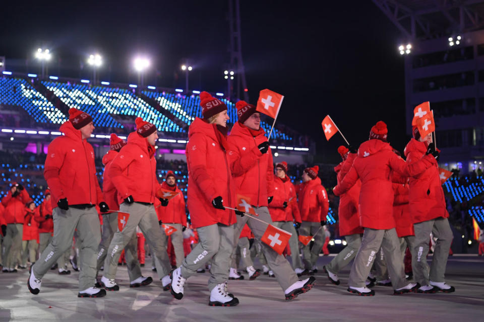 <p>Swiss athletes take part in the Team Parade wearing crimson winter jackets, gray pants, and pom-pom beanies during the opening ceremony of the 2018 PyeongChang Games. (Photo: Quinn Rooney/Getty Images) </p>