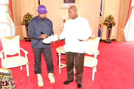 Rapper Kanye West (L) autographs a shoe as he meets Uganda's President Yoweri Museveni when he paid a courtesy call at State House, Entebbe, Uganda October 15, 2018. Presidential Press Unit/Handout via REUTERS
