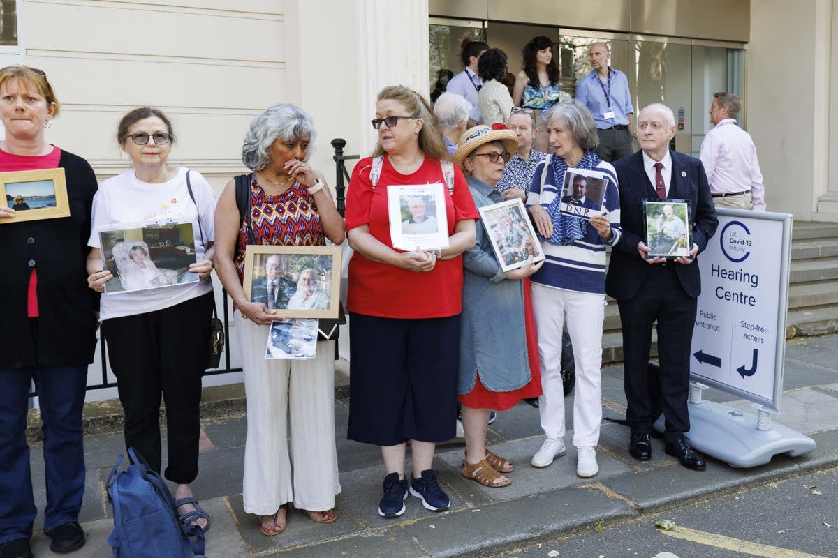 People hold pictures of loved ones lost during the pandemic outside the UK Covid-19 Inquiry at Dorland House in London (Belinda Jiao/PA) (PA Wire)