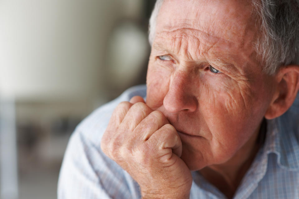 An elderly man in deep thought with his chin resting on the palm of his hand.